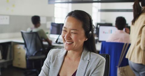 Smiling Asian Businesswoman in Modern Office on Headset