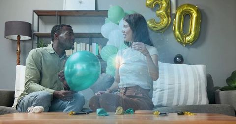 Couple preparing birthday balloons on sofa with gold 30 balloon celebrating milestone party