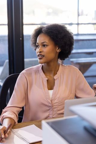 Professional african american woman writing at office desk