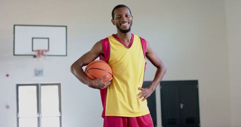Confident basketball player smiling in indoor gym