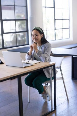 Asian woman using laptop in modern coworking space