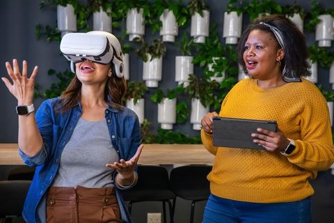 Female coworkers exploring virtual reality collaboration in modern office space