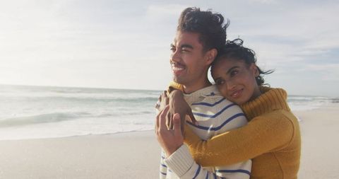 Happy hispanic couple embracing on sunny beach