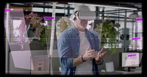 Mature man wearing VR headset gesturing to holographic AR panels in modern office