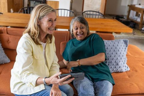 Senior women enjoying virtual reality experience at home laughing together