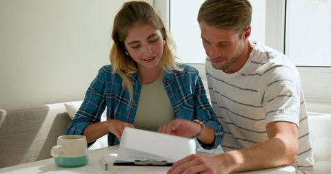 Couple reviewing documents together at home in bright morning