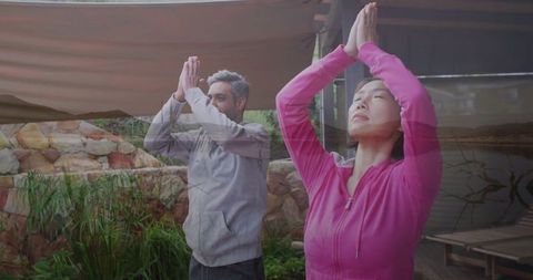 Couple practicing yoga prayer pose outdoors for wellness
