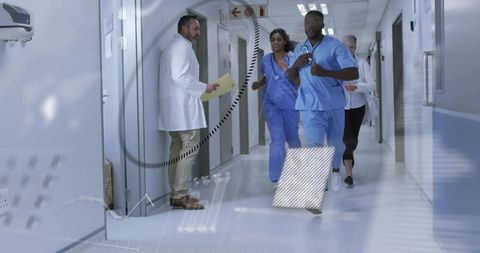 Medical team running urgent response in hospital corridor with file and stethoscopes