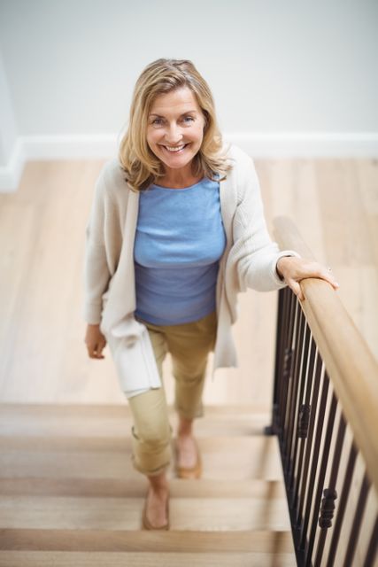 Portrait of smiling senior woman climbing upstairs at home