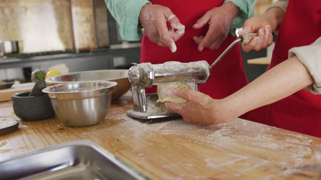 Senior man and woman engaged in an interactive cooking class in restaurant kitchen, working as a team to make fresh pasta. Highlighting focus on traditional cooking methods, this scene offer inspiration for culinary workshops, teamwork activities, or home-cooked meals on websites and promotional materials.