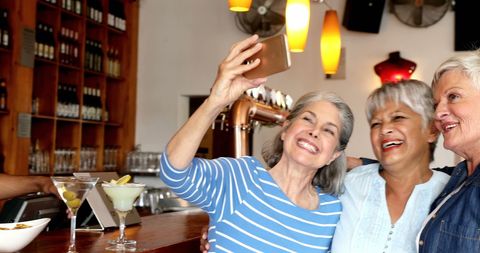 Joyful Women Friends Taking Selfie in Vibrant Bar