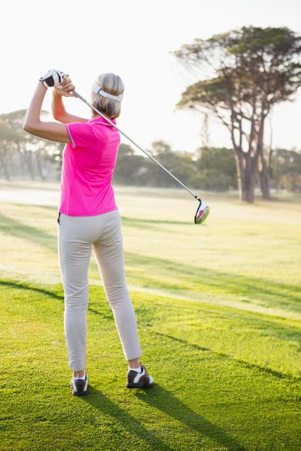 Rear view of sportswoman playing golf on field