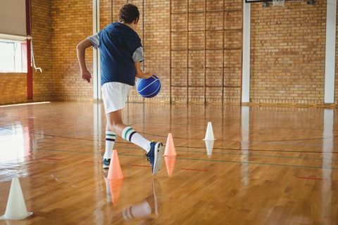 Young Athlete Dribbling Basketball in School Gymnasium