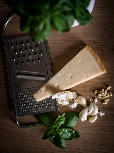 A cheese slice on a grated topping with fresh basil, garlic cloves, and pine nuts. Ideal for use in food blogs, recipe books, culinary websites, or advertisements focusing on cooking ingredients or Italian cuisine.