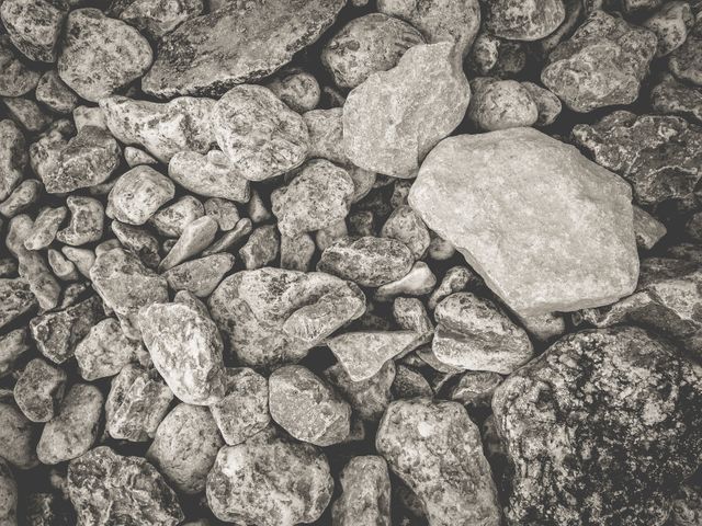 Close-up view of assortment of textured rocks in black and white. Useful for backgrounds, geology presentations, design projects, or nature-themed artworks. Emphasizes rugged and natural elements with an abstract touch.
