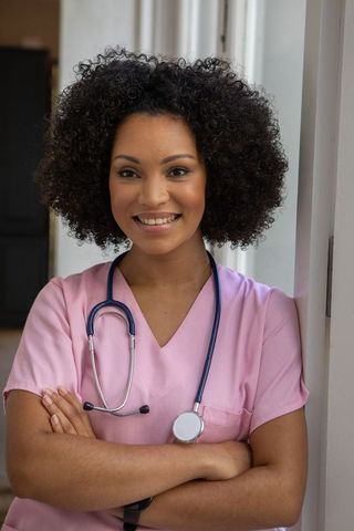 Confident nurse in pink scrubs smiling with stethoscope
