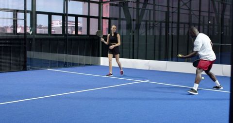 Diverse Players Engaged in Fast-Paced Padel Match on Blue Court