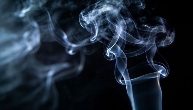 Bluish-white smoke plume rising, twisting and curling on black background