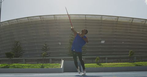 Athlete practicing javelin throw in outdoor stadium setting