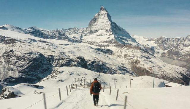 Hiker walking toward matterhorn on snowy alpine trail with backpack and solitude
