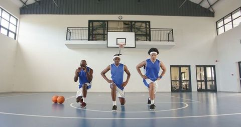 Basketball Players Warming Up with Lunges on Indoor Court