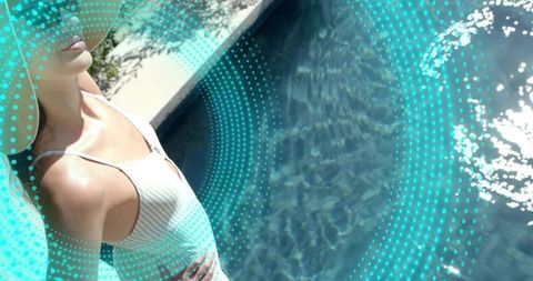 Poolside woman in white one-piece swimsuit and straw hat relaxing by turquoise water