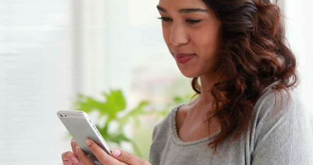 Young Woman Smiling While Using Smartphone in Bright Room - Download Free Stock Images Pikwizard.com