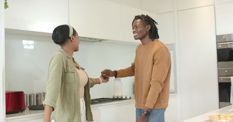 African American Couple Holding Hands and Smiling in Modern Bright Kitchen Together