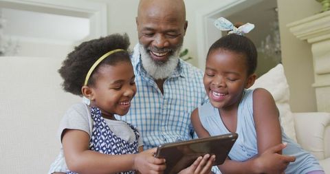 Grandfather Enjoying Tablet Time with Granddaughters at Home