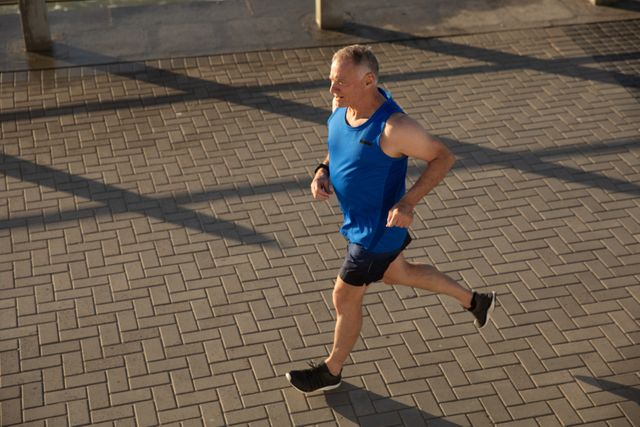 Senior Caucasian man working out on promenade by the sea wearing sports clothes, running. Retirement healthy lifestyle activity.