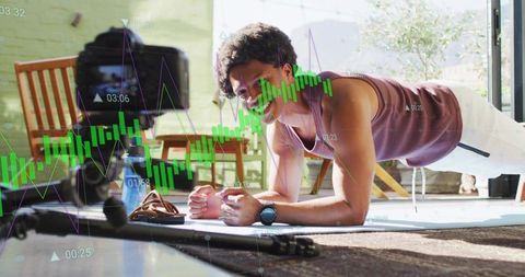 Man holding forearm plank on mat, home workout streaming with analytics and candlestick graphs