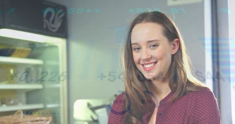 Smiling young professional in red print blouse in office kitchen with data overlay