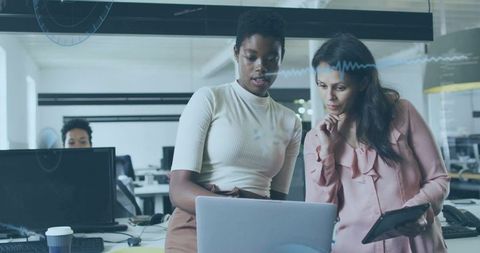 Colleagues collaborating over laptop in modern open-plan office workspace