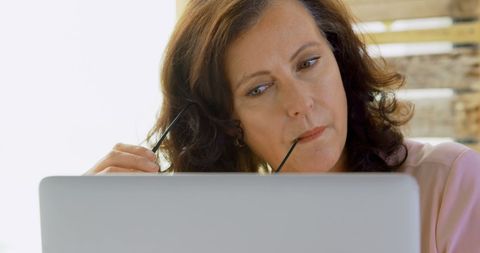 Pensive Businesswoman Analyzing Data on Laptop