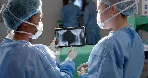 Surgeons Examining Spinal X-rays on Tablet in Operating Room