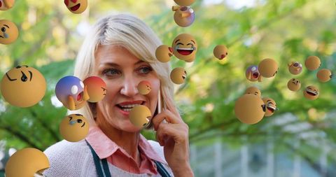 Cheerful Woman Conversing on Smartphone with Floating Emojis Outdoors