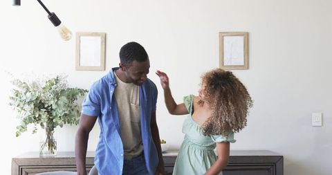 Couple sharing playful moment in modern minimalist living room with greenery