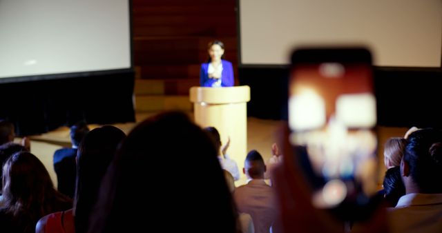 Close-up of businesswoman recording lecture during business seminar in auditorium. She is using mobile phone 4k