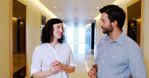 Colleagues Engaging in Corridor Discussion at Modern Office