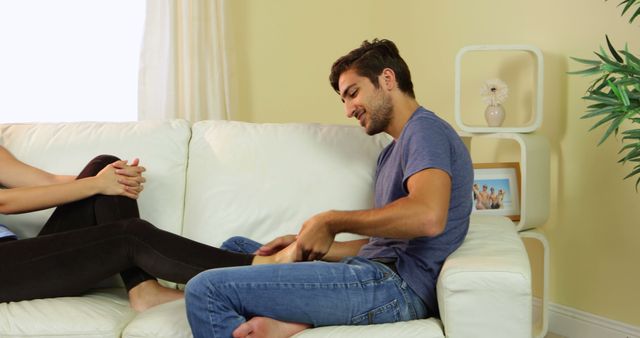 Young Man Giving Foot Massage to Woman on Sofa in Cozy Living Room - Download Free Stock Images Pikwizard.com