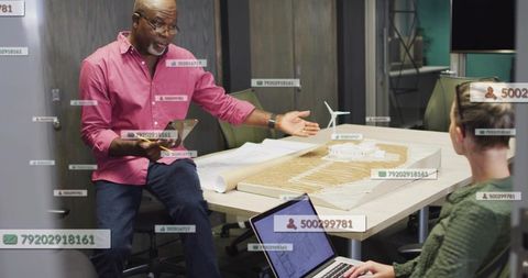 Gesturing designer explaining wind turbine site model during collaborative planning meeting