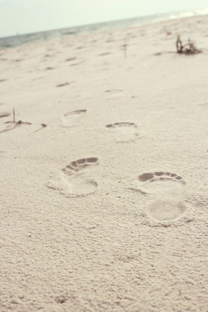 Footprints spacing through white sandy beach creating sense of solitary morning walk. Ideal for travel blogs, nature journals, beach-themed projects, promoting coastal tourism, and creating calm, serene visuals.