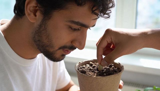 Young man planting coin in biodegradable pot symbolizing finance growth and nurture