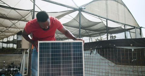 Man installing solar panel in modern greenhouse