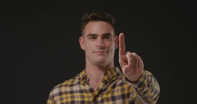 Man pointing with index finger in checkered shirt against black background - Download Free Stock Images Pikwizard.com