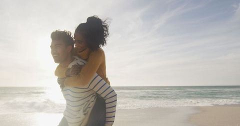 Joyful Couple Piggyback on Sandy Beach at Sunset