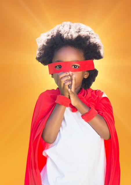 Girl in superhero costume with hands joined together against orange background