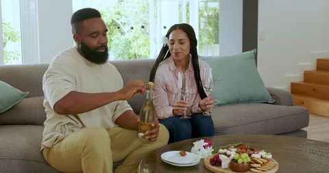Couple celebrating anniversary with wine and snacks at home