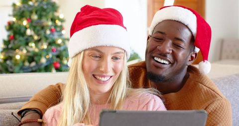 Happy Couple Sharing Holiday Moments on Tablet by Christmas Tree