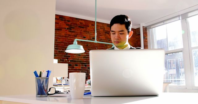 Young Professional Working on Laptop in Modern Office Environment - Download Free Stock Images Pikwizard.com